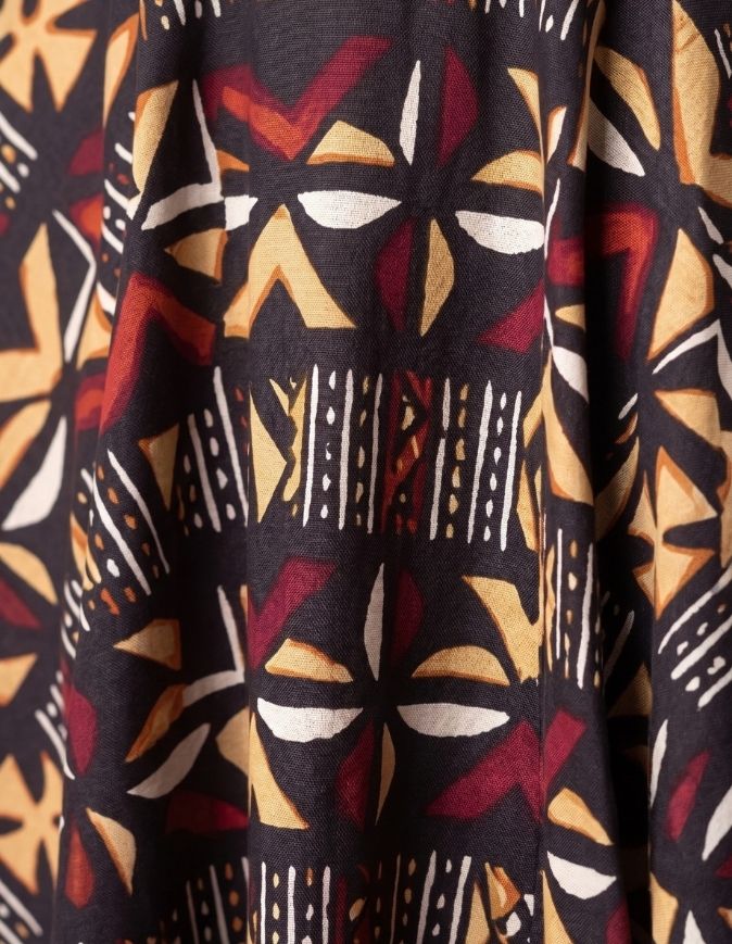 Femme portant une jupe patineuse mi-longue en bogolan aux motifs géométriques chaleureux, taille unique extensible
