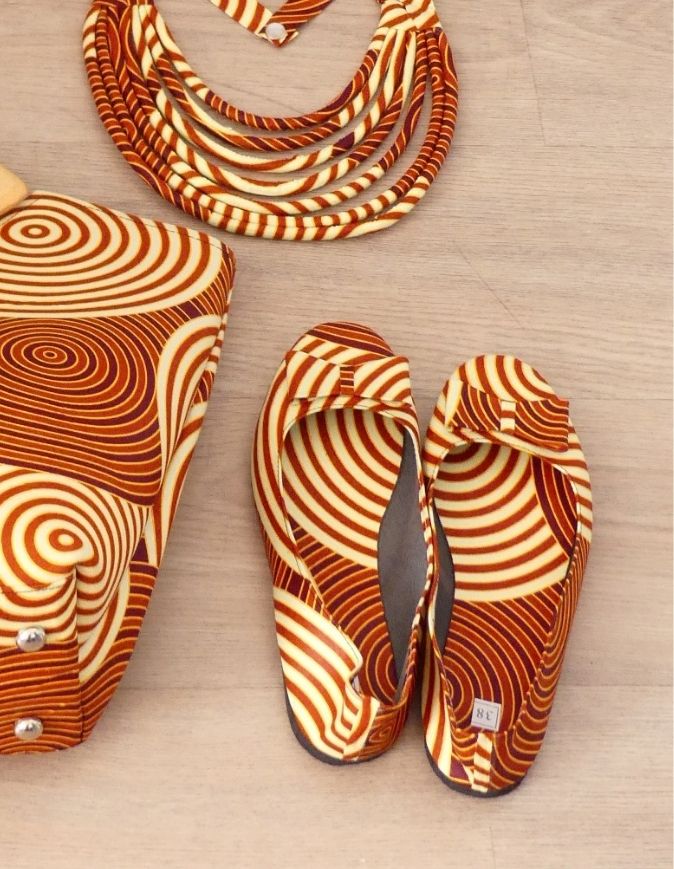 Pieds de femme portant des sandales plates en wax rouge et beige, taille 38