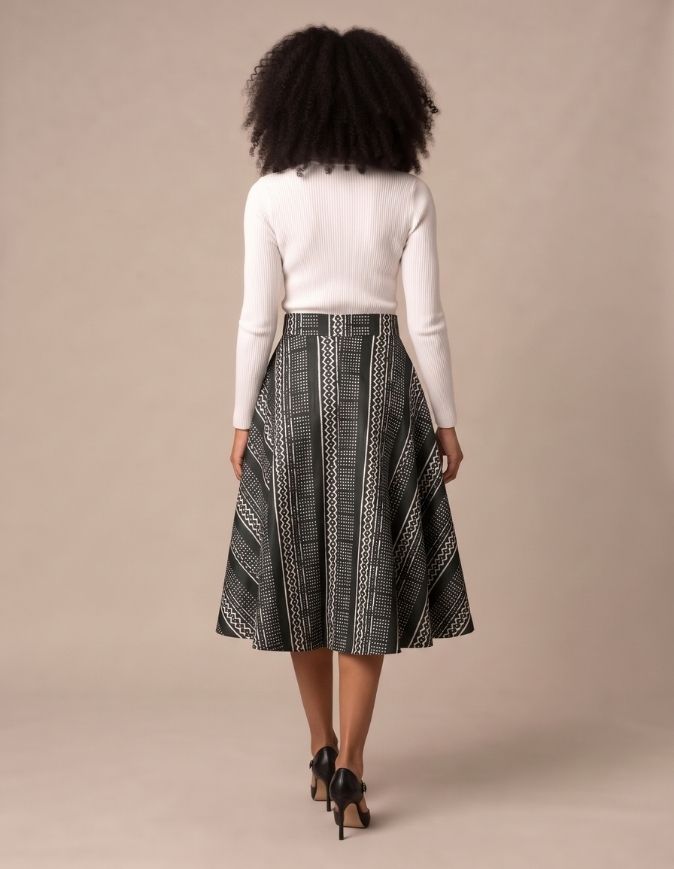 Femme portant une jupe patineuse mi-longue en bogolan noir et blanc aux motifs géométriques, taille unique extensible