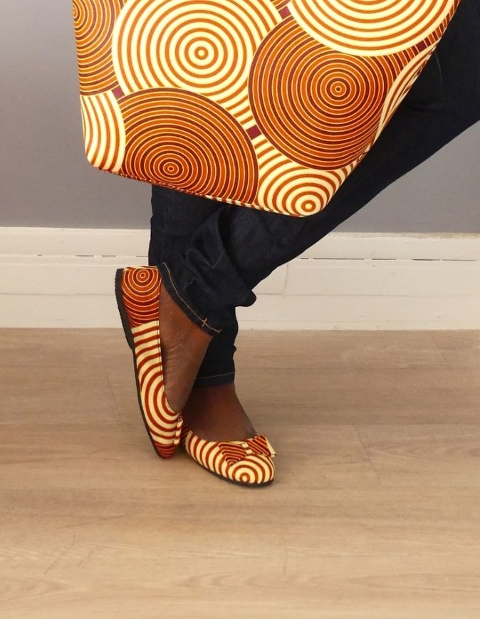 Pieds de femme portant des sandales plates en wax rouge et beige, taille 38